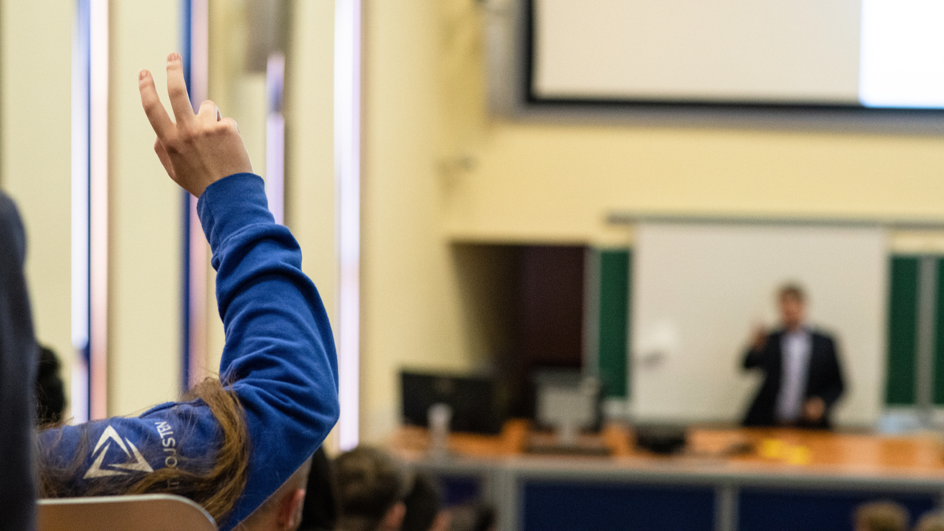 A hand is raised in the lecture hall