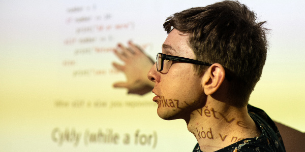 Lecturer standing illuminated by Python code slides